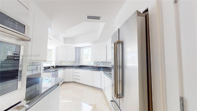 kitchen with stainless steel appliances, white cabinets, backsplash, sink, and light tile floors