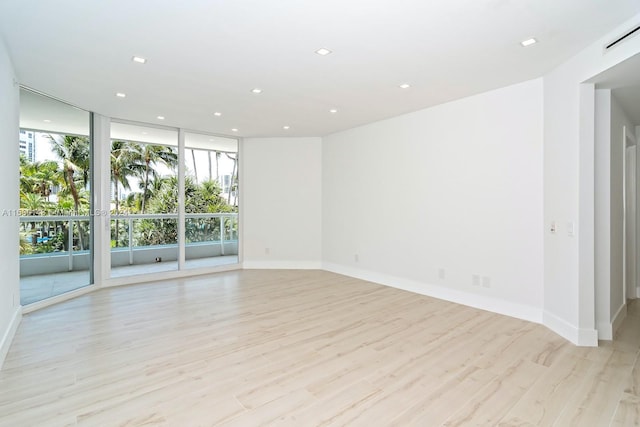 unfurnished room featuring expansive windows and light hardwood / wood-style floors