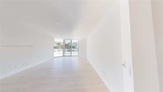 spare room featuring expansive windows and light hardwood / wood-style floors