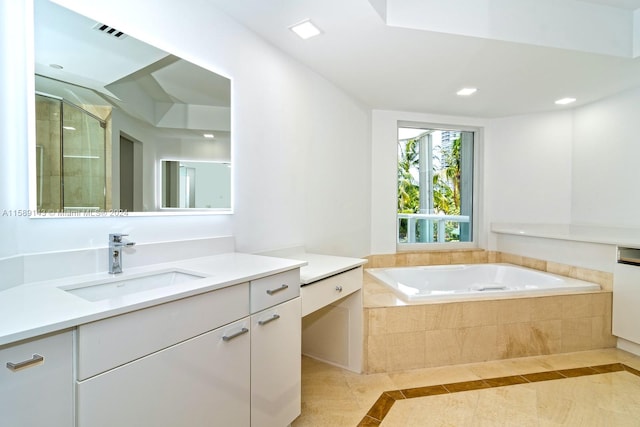 bathroom featuring tile floors, tiled tub, and vanity