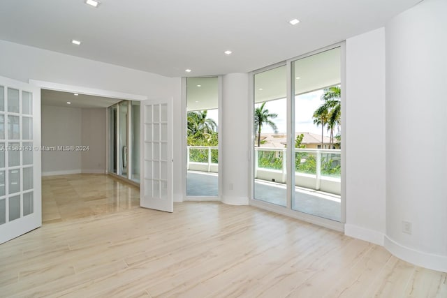 unfurnished room with light hardwood / wood-style flooring, floor to ceiling windows, and french doors