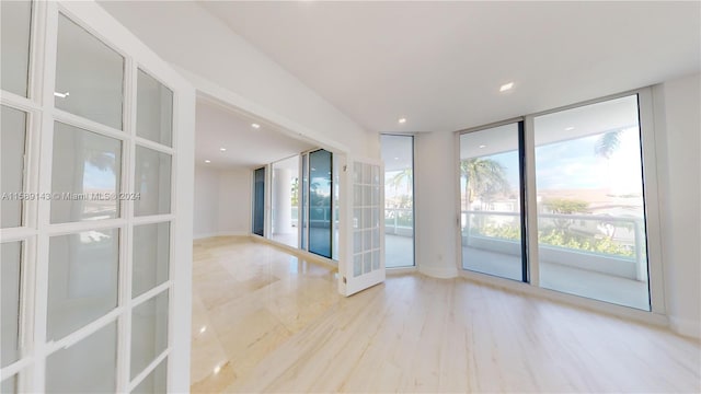 spare room featuring hardwood / wood-style flooring, french doors, and a wall of windows