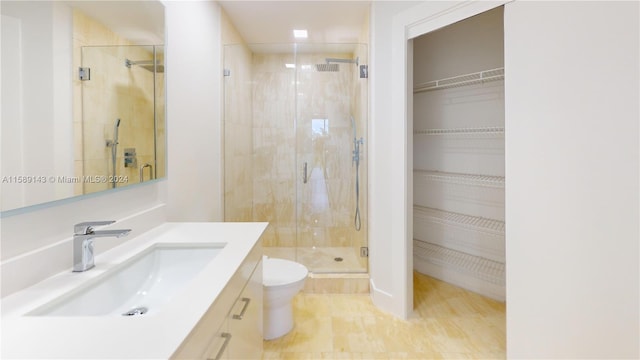 bathroom featuring hardwood / wood-style flooring, vanity, toilet, and a shower with door