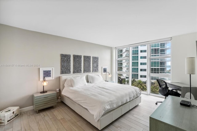 bedroom featuring access to outside, expansive windows, and light hardwood / wood-style floors