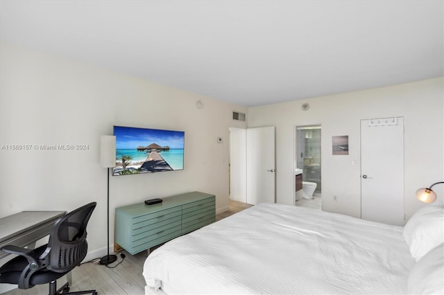 bedroom with light hardwood / wood-style floors and ensuite bath