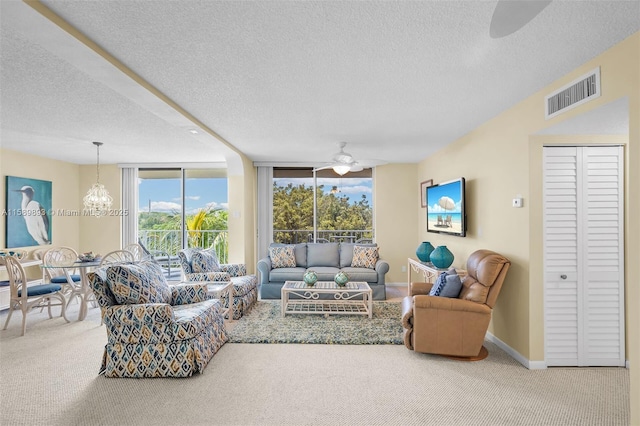 carpeted living room featuring visible vents, a textured ceiling, baseboards, and ceiling fan with notable chandelier