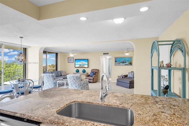 kitchen with carpet flooring, sink, ceiling fan, and a textured ceiling