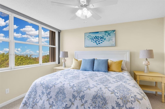 carpeted bedroom with ceiling fan and a textured ceiling