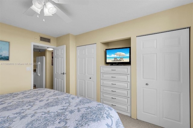 bedroom featuring carpet, visible vents, ceiling fan, and two closets