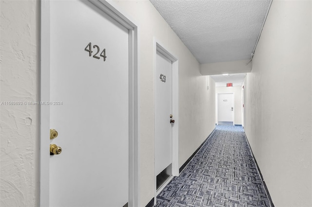 corridor with dark tile flooring and a textured ceiling