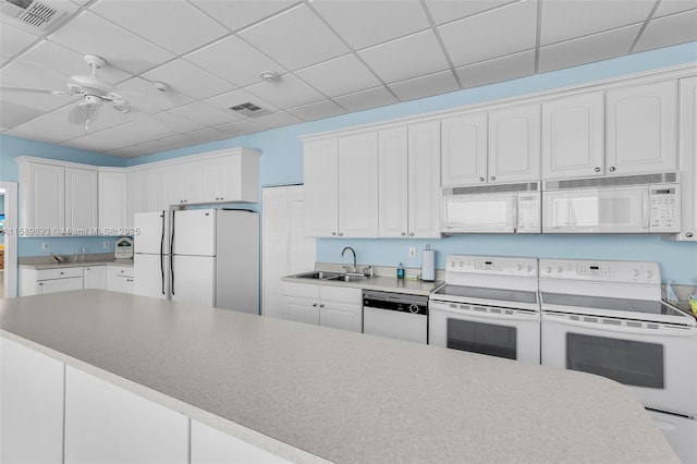 kitchen featuring visible vents, white cabinets, a sink, white appliances, and a drop ceiling