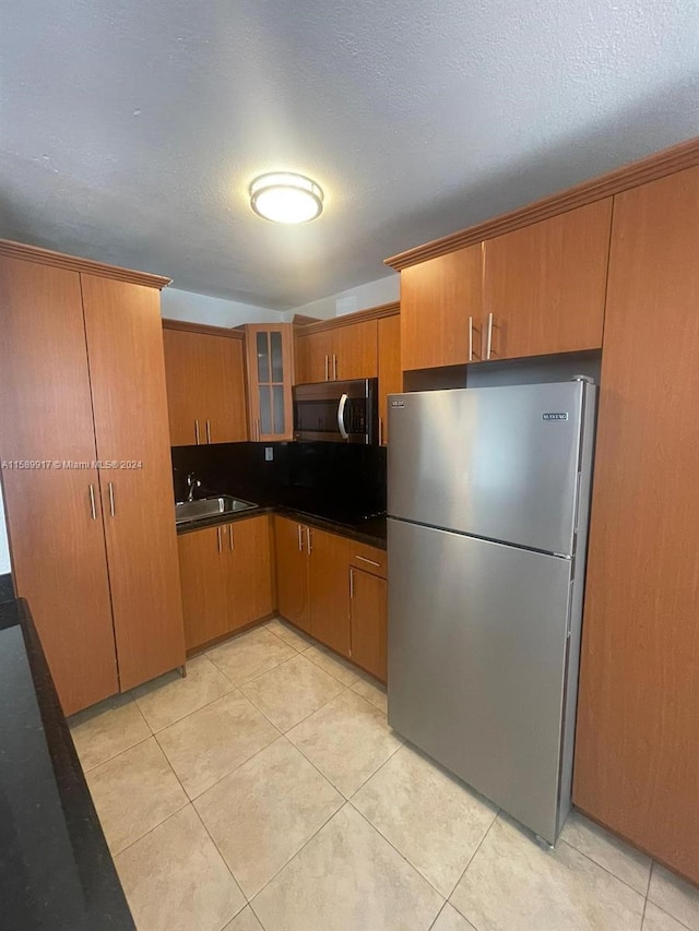 kitchen with sink, light tile flooring, a textured ceiling, and stainless steel appliances