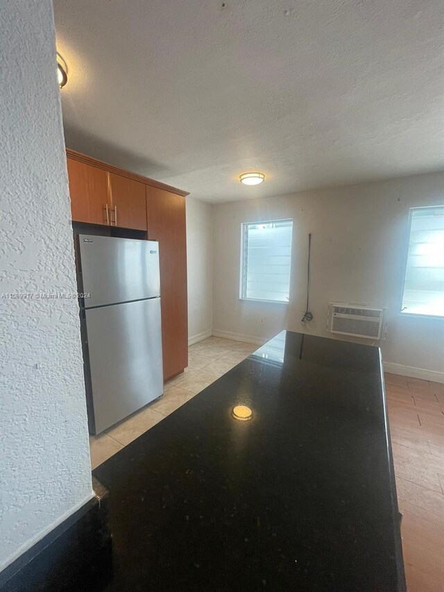 kitchen with plenty of natural light, a wall mounted AC, stainless steel fridge, and a textured ceiling