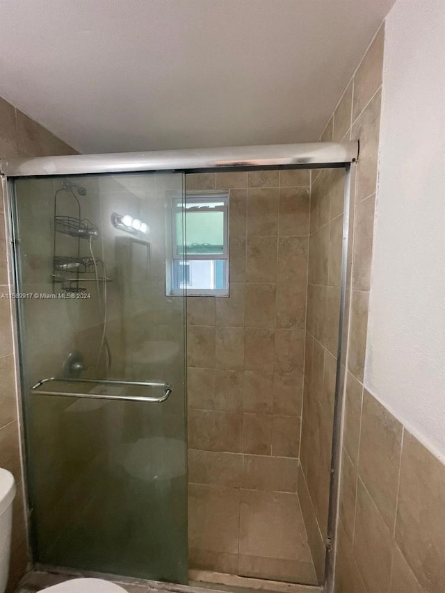 bathroom with a shower with door and toilet