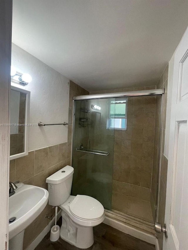 bathroom with a shower with shower door, tile walls, toilet, and hardwood / wood-style flooring