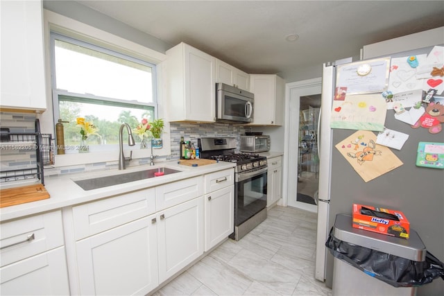 kitchen with decorative backsplash, sink, white cabinets, and stainless steel appliances