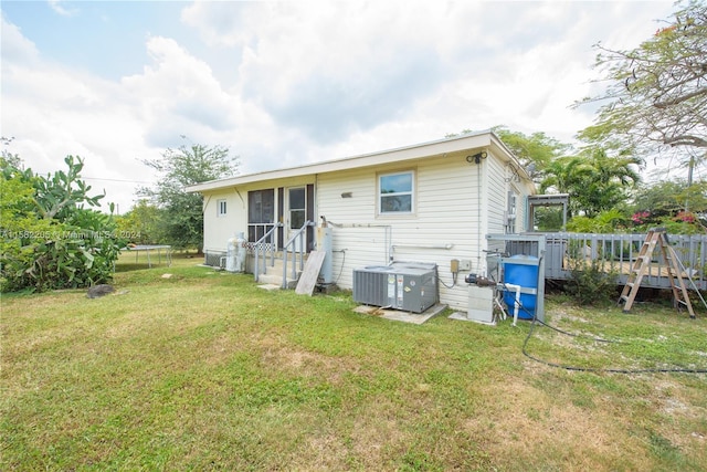 rear view of house featuring a lawn, central air condition unit, and a wooden deck