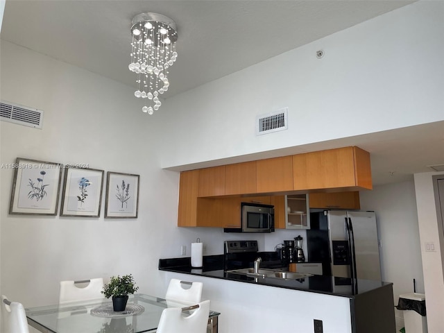 kitchen with stainless steel appliances, kitchen peninsula, a notable chandelier, sink, and a kitchen bar