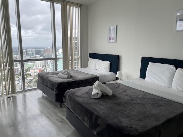 bedroom featuring floor to ceiling windows, wood-type flooring, access to outside, and multiple windows