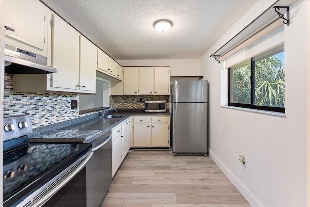 kitchen featuring light hardwood / wood-style flooring, tasteful backsplash, stainless steel appliances, a textured ceiling, and sink