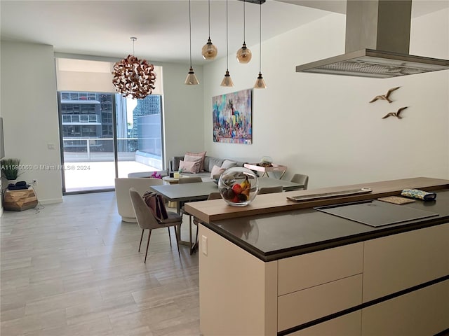 kitchen with wall chimney range hood, a notable chandelier, hanging light fixtures, and floor to ceiling windows