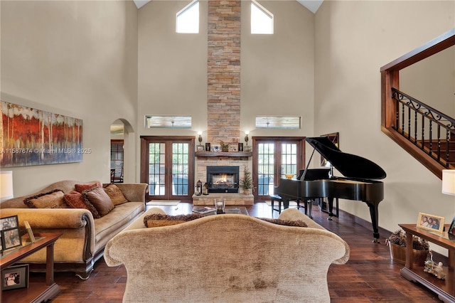 living room featuring french doors, a high ceiling, dark wood-type flooring, and a fireplace