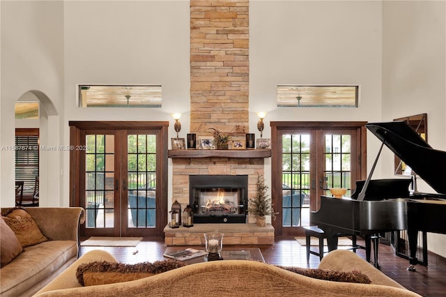 sitting room featuring french doors, a high ceiling, a fireplace, and wood-type flooring