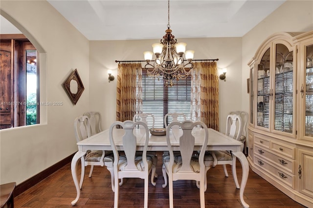 dining space with a raised ceiling, an inviting chandelier, and dark hardwood / wood-style floors