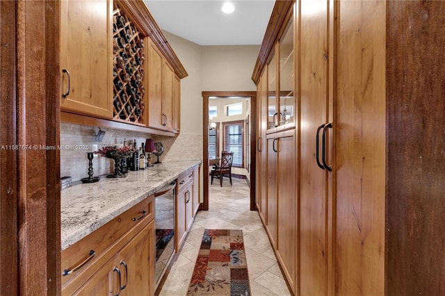 bar with light stone counters, backsplash, beverage cooler, and light tile patterned flooring