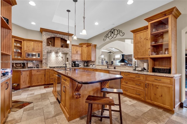 kitchen featuring decorative backsplash, a kitchen breakfast bar, appliances with stainless steel finishes, and an island with sink