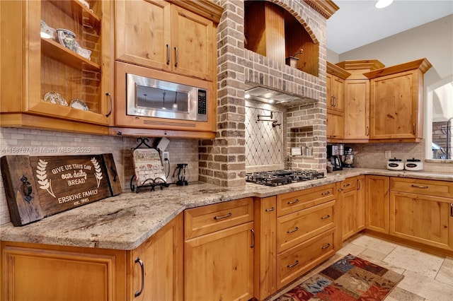 kitchen with light stone counters, decorative backsplash, and appliances with stainless steel finishes