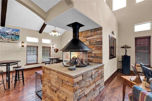 kitchen with a wood stove, dark hardwood / wood-style flooring, beam ceiling, and a towering ceiling