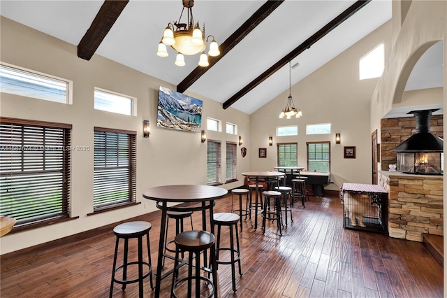 dining area with beam ceiling, a high ceiling, an inviting chandelier, and dark wood-type flooring