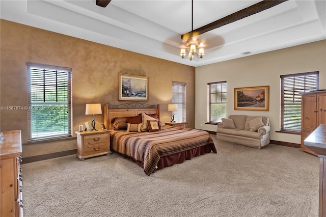 carpeted bedroom with a raised ceiling and a chandelier