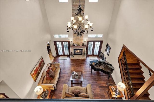 living room with a towering ceiling, french doors, dark hardwood / wood-style flooring, and a stone fireplace