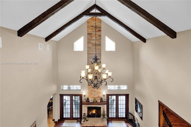 interior space with a fireplace, beam ceiling, high vaulted ceiling, and french doors