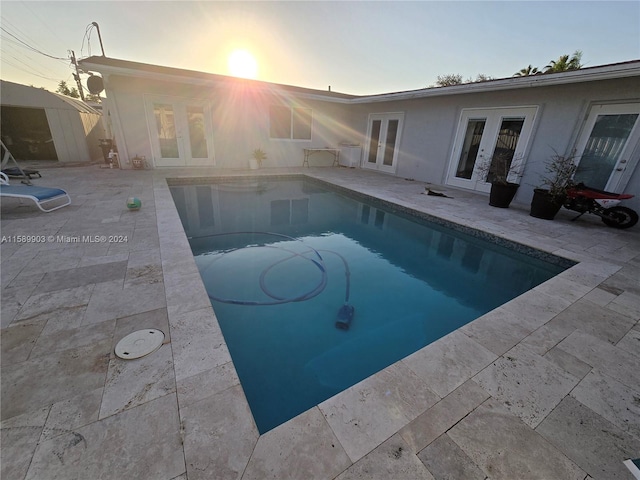 pool at dusk featuring a patio area and french doors