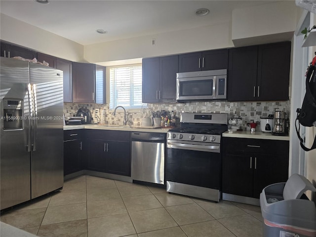 kitchen with appliances with stainless steel finishes, sink, tasteful backsplash, and light tile floors