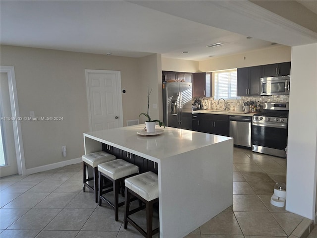 kitchen with a kitchen island, stainless steel appliances, backsplash, sink, and light tile floors