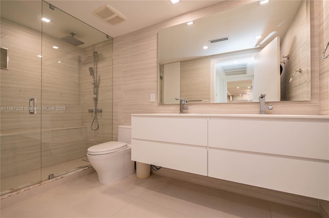 full bath with toilet, visible vents, tile walls, a shower stall, and double vanity