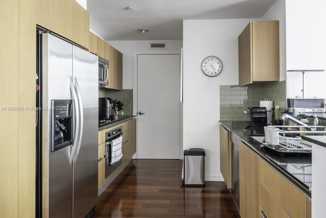 kitchen with dark hardwood / wood-style floors, tasteful backsplash, light brown cabinetry, dark stone countertops, and appliances with stainless steel finishes