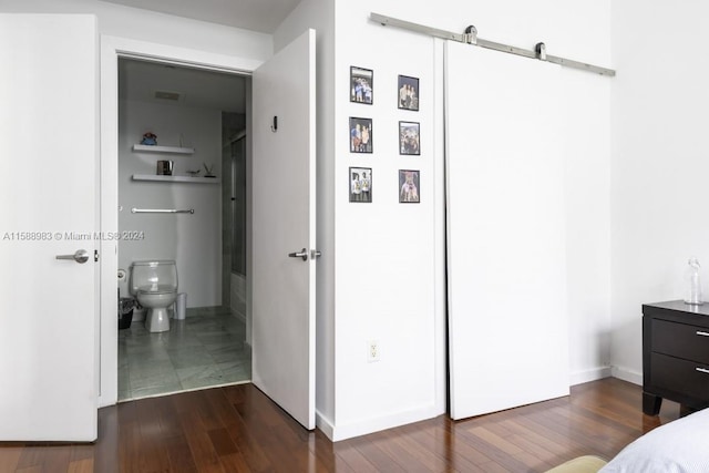 bedroom featuring dark hardwood / wood-style floors and a barn door