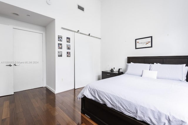 bedroom featuring a closet, dark hardwood / wood-style floors, and a barn door