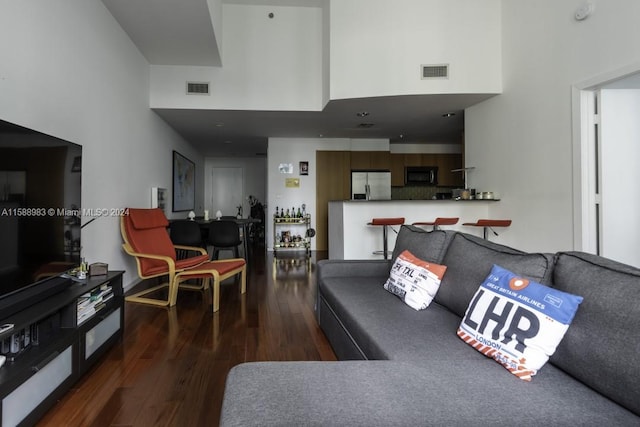 living room featuring a towering ceiling and dark hardwood / wood-style flooring