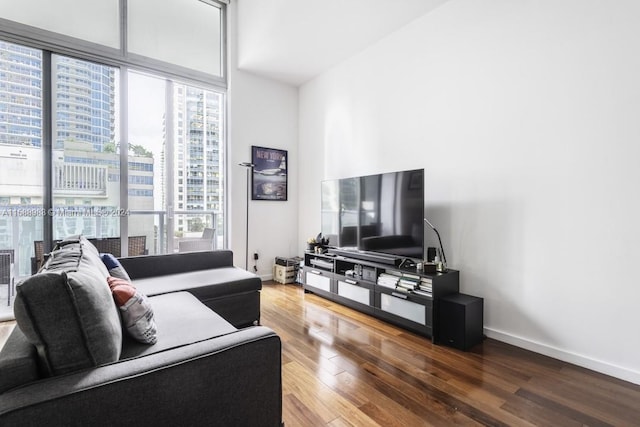 living room featuring floor to ceiling windows, a towering ceiling, and hardwood / wood-style flooring