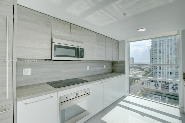 kitchen featuring oven, black electric stovetop, and expansive windows