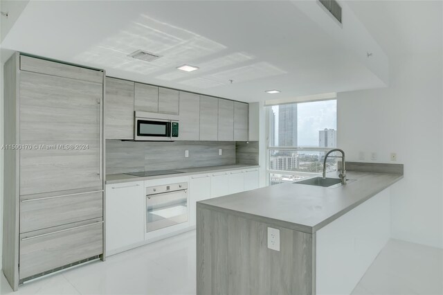 kitchen featuring white appliances, light tile patterned floors, gray cabinets, decorative backsplash, and sink