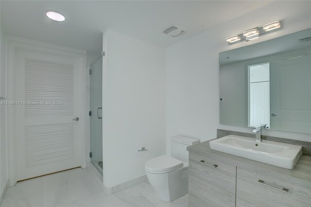 bathroom with vanity, toilet, a shower with door, and tile patterned floors