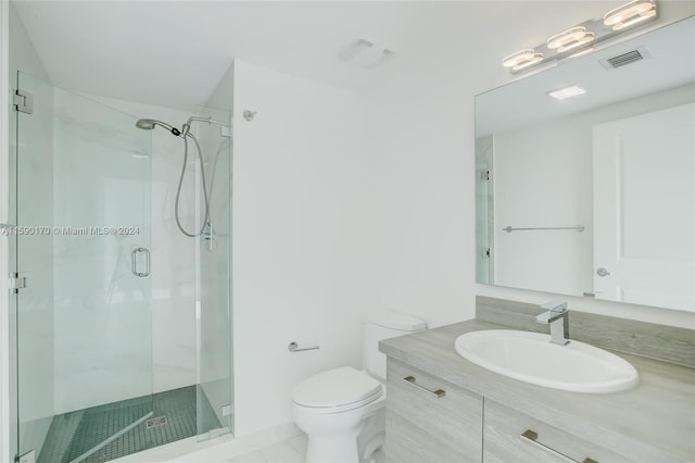 bathroom with a shower with door, vanity, tile patterned flooring, and toilet