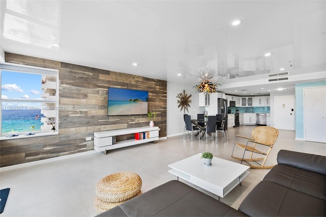 living room with wood walls, light tile flooring, and a water view